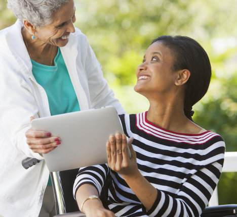 caregiver and patient holding a tablet while looking at each other