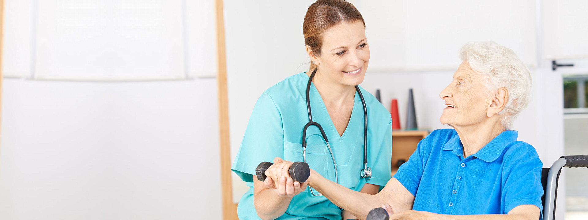 caregiver assisting  elderly patient in lifting weights